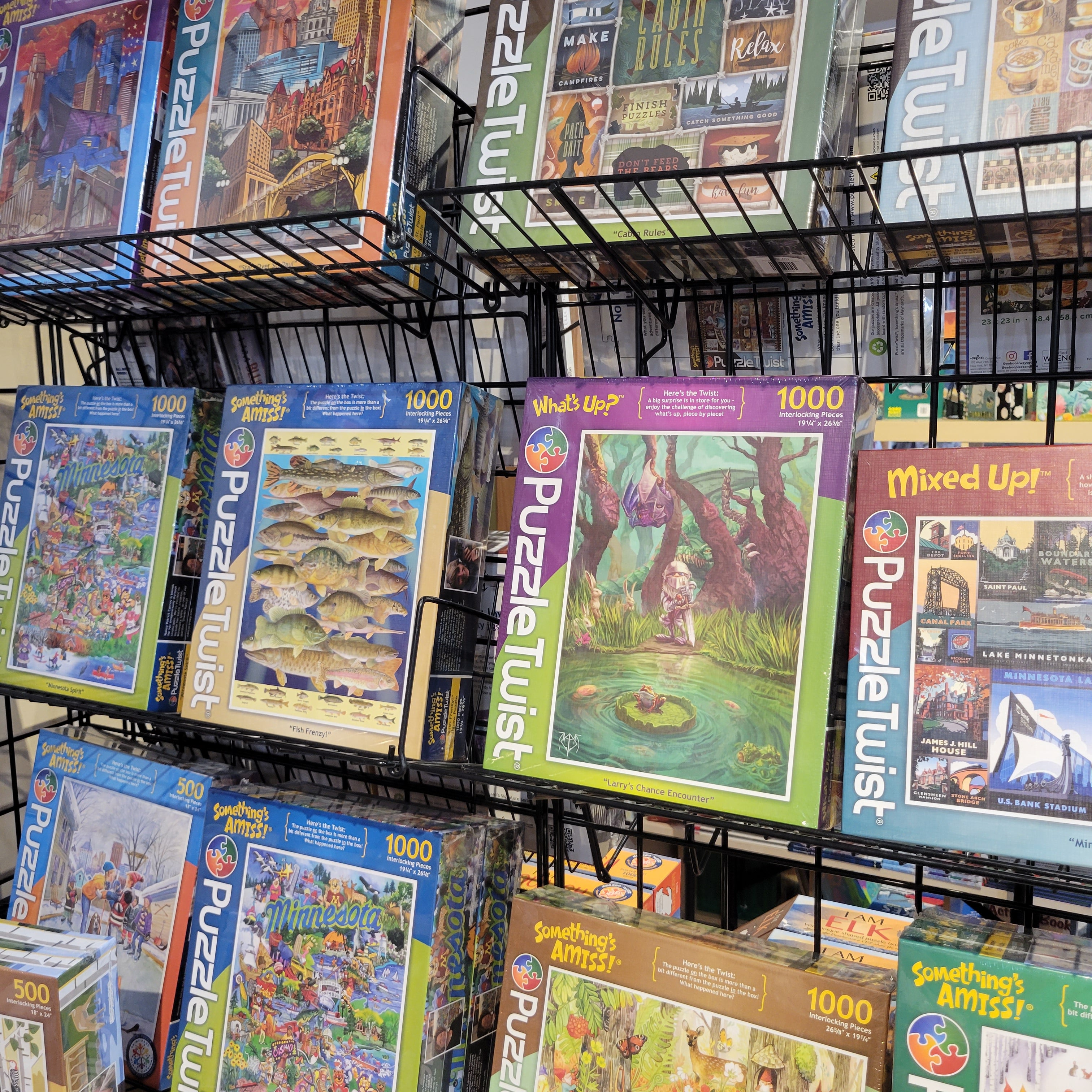 A display shelf featuring various jigsaw puzzles in colorful boxes with themes like nature, art, and architecture.