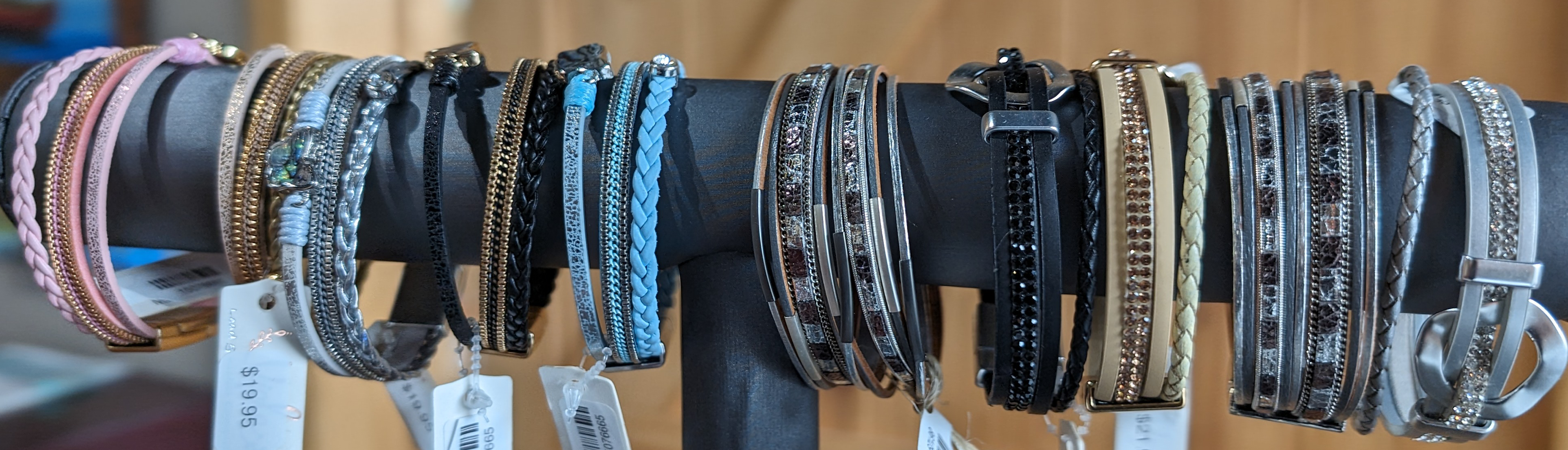 A display rack holds an assortment of bracelets in various colors and designs, each with a price tag attached.