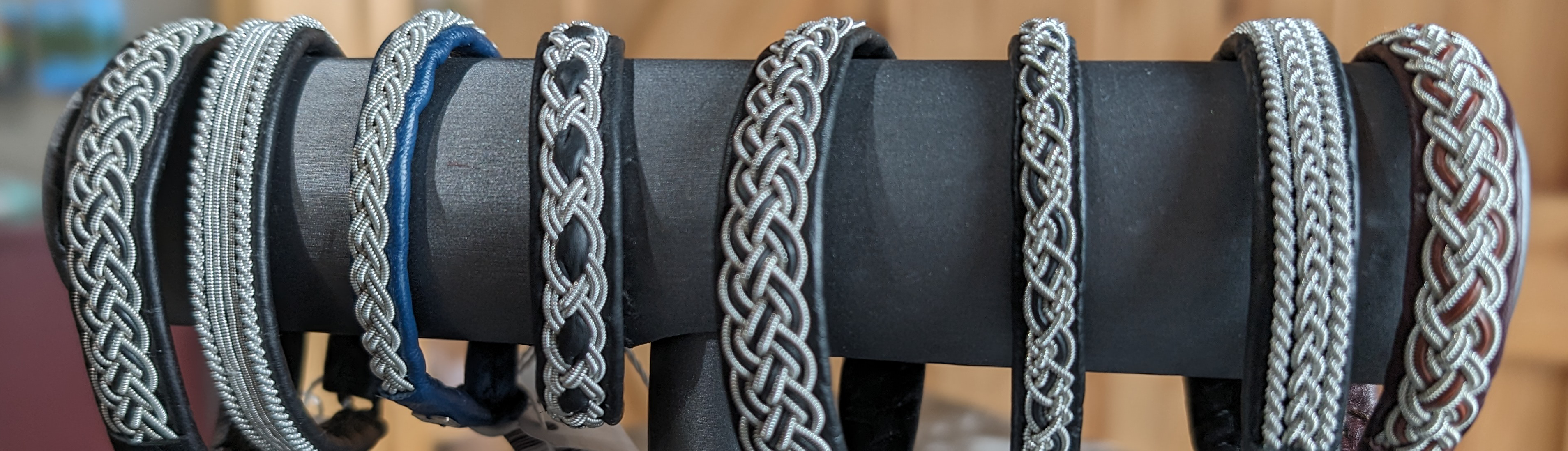 A display of intricately braided bracelets on a black stand, showcasing various patterns and colors.