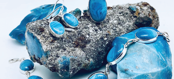 Silver jewelry with blue gemstones displayed on rough, textured gray rocks.