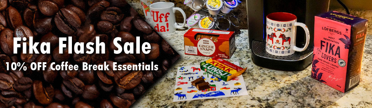Kitchen countertop with a coffee maker, various coffee pods, a decorated mug, a Lofbergs Fika coffee box, ginger snaps, and a chocolate bar on Swedish-themed packaging.