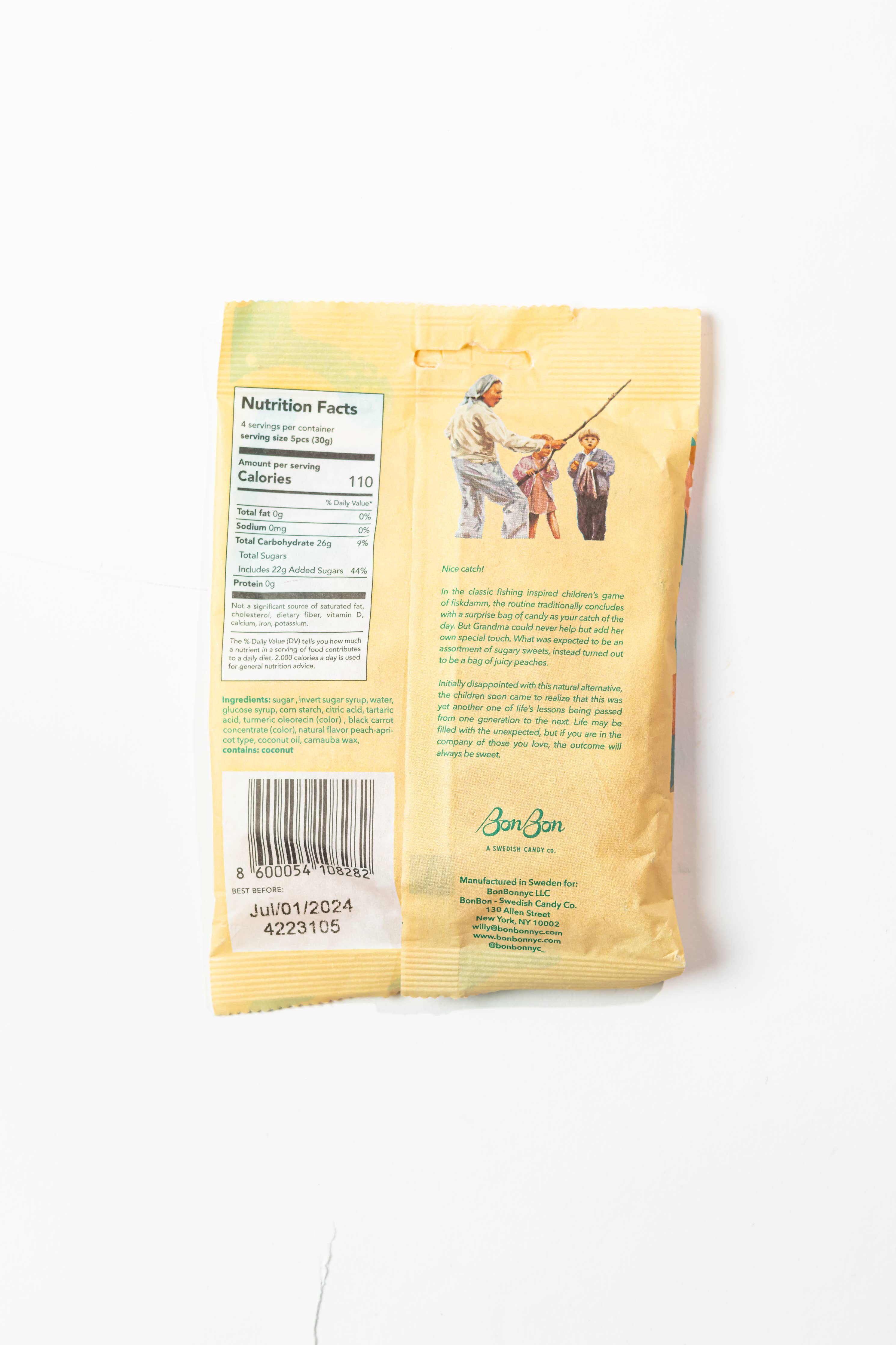 Back of BonBon - Sour Peach Fish (150g) package displays nutrition facts, barcode, a short story, and an illustration of a man fishing with two children. Enjoy this delicious Swedish vegan candy!.