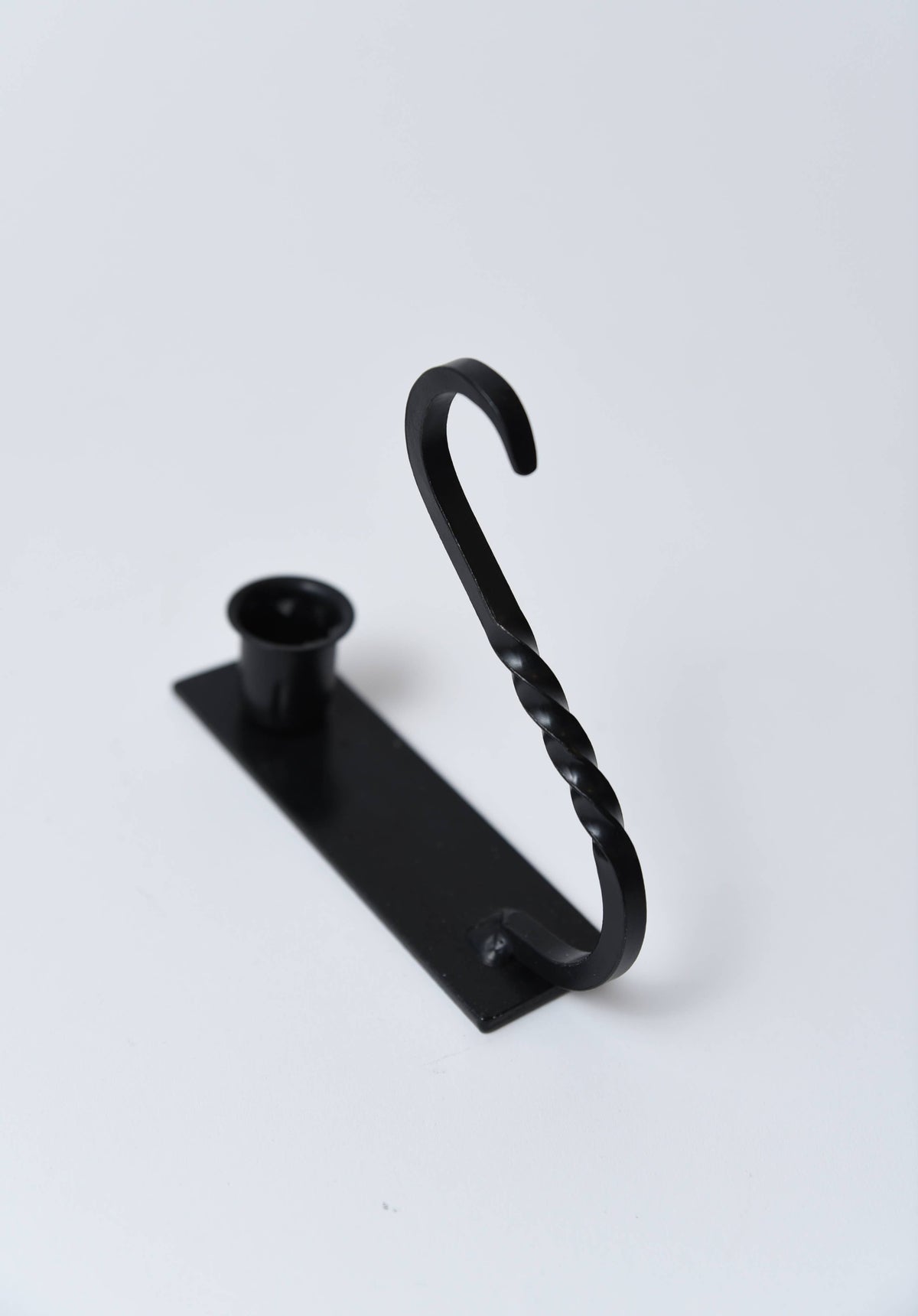Iron taper holder with a rectangular base, circular candle cup, and a twisted S-shaped wall-mounting hook.