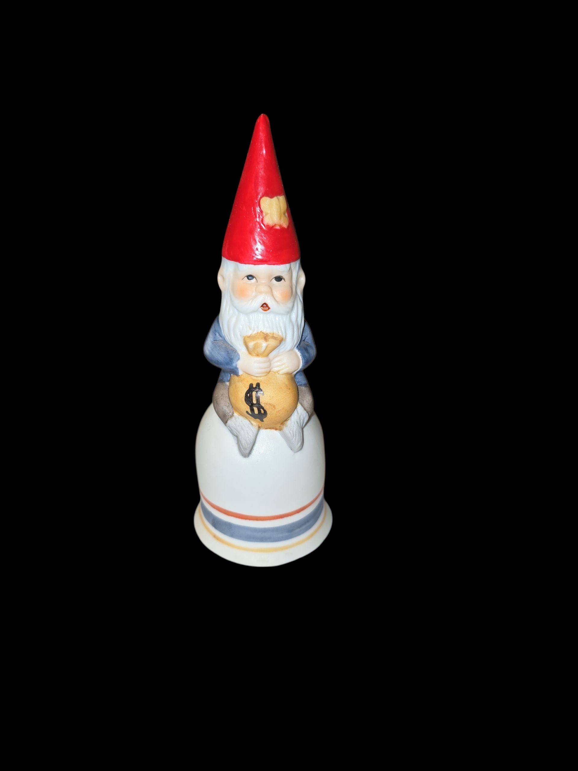 The Bell: Tomte Sitting on a Bell Holding a Bag of Money is a 5.75 tall x 2 wide figurine featuring a gnome with a red hat and money bag, shown against a black background.