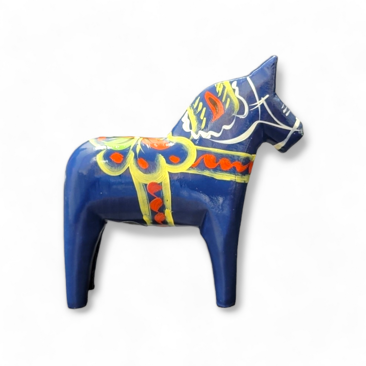 Hand-carved Dala Horse in blue adorned with vibrant yellow and red kurbits patterns, set against a white background.