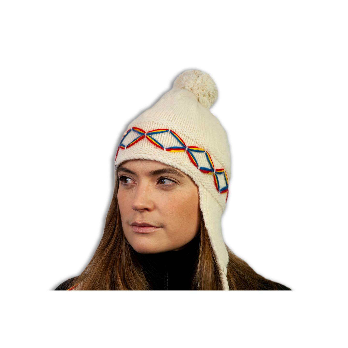 A woman wearing a light grey Borjesson Handskar "Lovikka" knit wool hat with earflaps, a pompom on top, and a geometric Nordic pattern on the band.