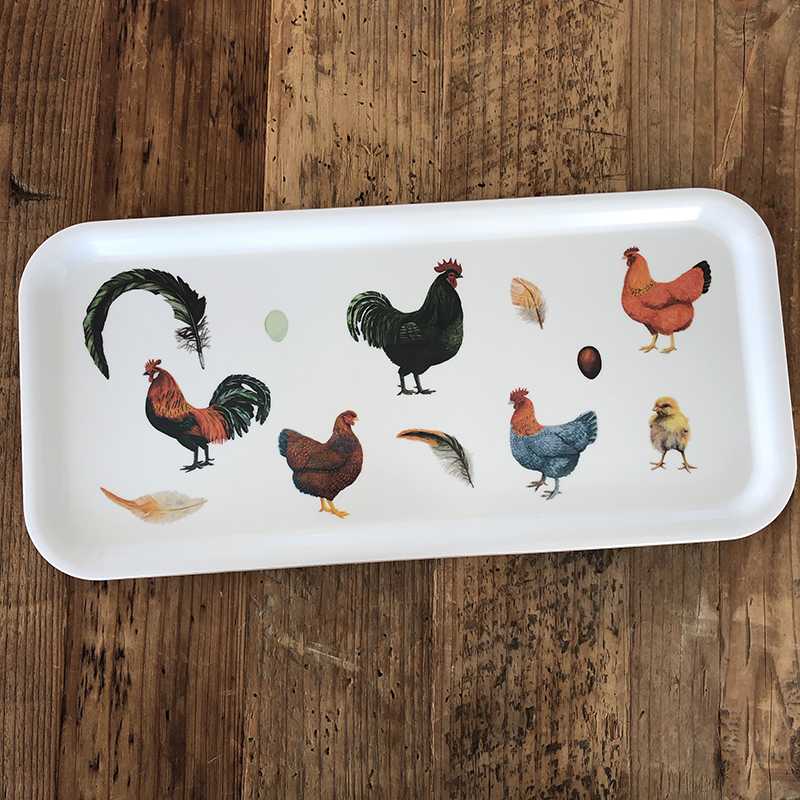 The Tray: Colorful Hens features illustrations of chickens, feathers, and eggs on a white background. This eco-friendly serving tray is made with a melamine coating on birch veneer and measures 6 x 12 inches.
