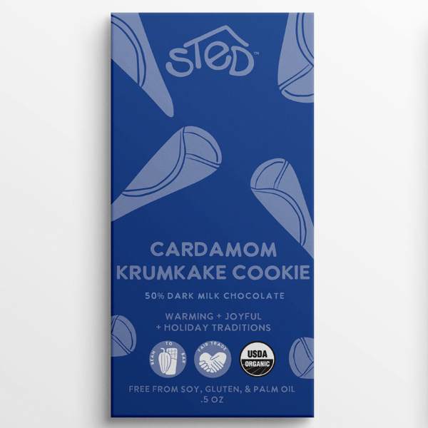 Blue wrapper with text: “Sted Cardamom Krumkake Cookie, 50% dark milk chocolate,” visible Scandinavian mention; symbols for organic, soy-free, gluten-free, palm oil–free.