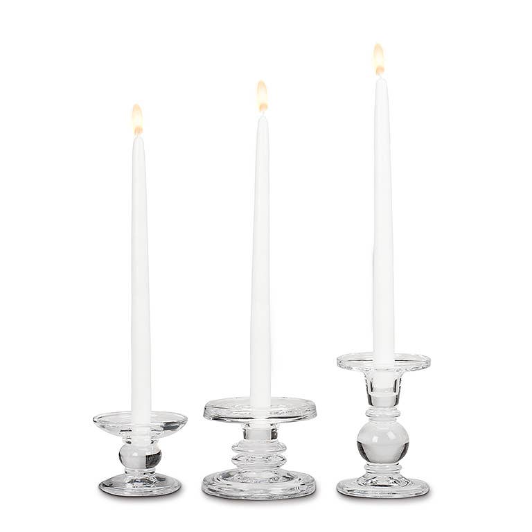 A lit white taper candle in the Small Reversible Candle Holder-3.5"L, elegantly displayed against a white background.