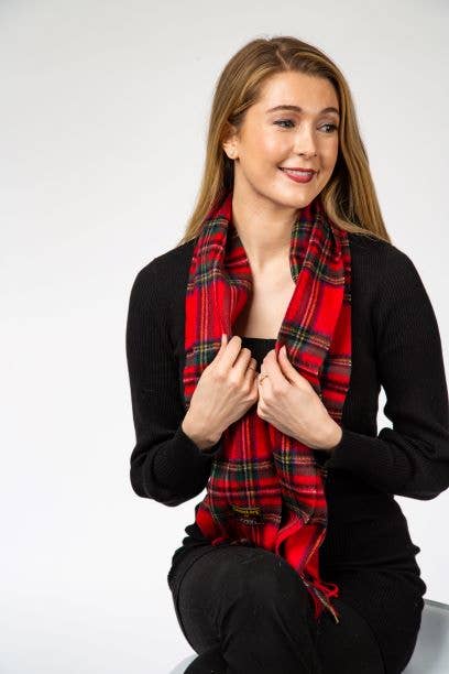 A woman with long hair sits, wearing a black top and a Royal Stewart Lambswool Scarf by Patrick King, smiling and looking slightly to her left against a plain white background.