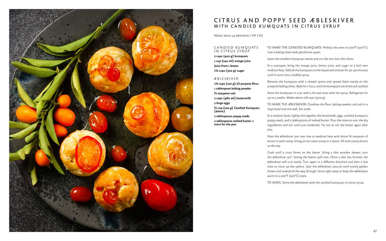 Six æbleskiver Danish pancakes topped with candied kumquats and cherries, served on a black plate with herbs and cherry tomatoes, beside the book Aebleskiver by Pim Pauline Overgaard: A New Take on Traditional Danish Pancakes.