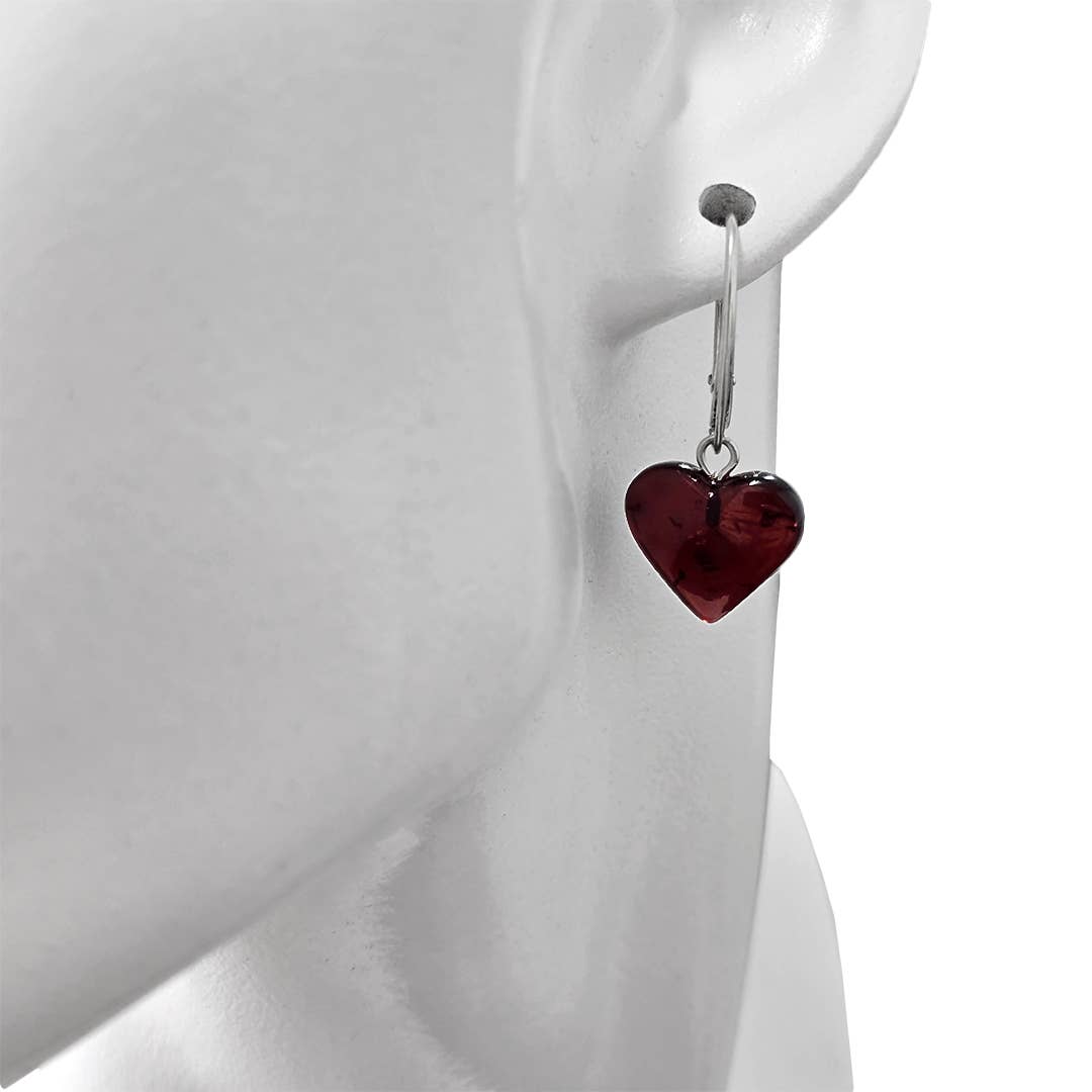 A close-up of a mannequin wearing Heart Cherry Amber Sterling Silver Earrings, featuring a dark red heart-shaped pendant.