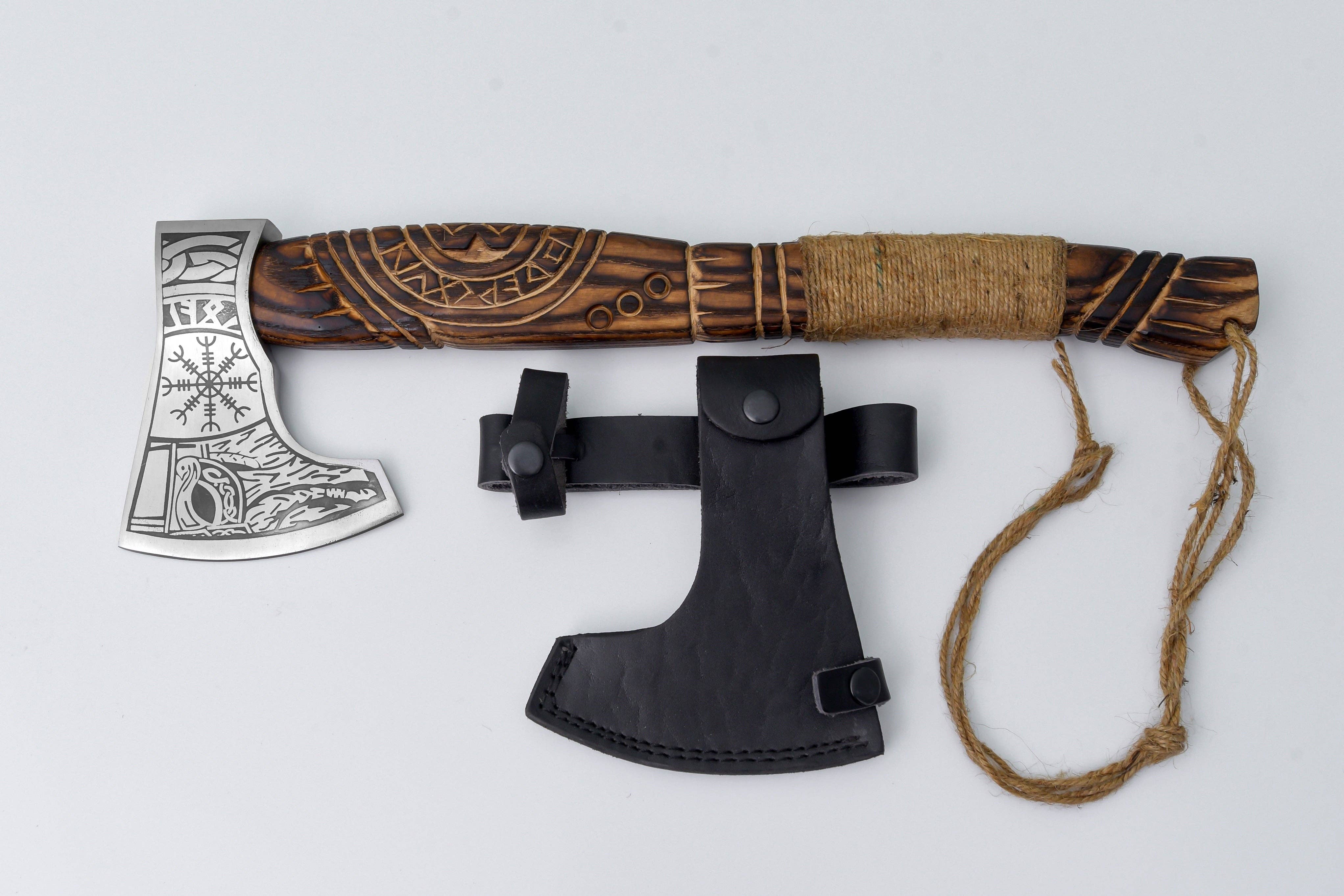 The Axe: Aegir’s Wrath Utility Camping Tool, featuring a carved wooden handle and wrapped grip, is shown next to a black leather sheath on a white background.