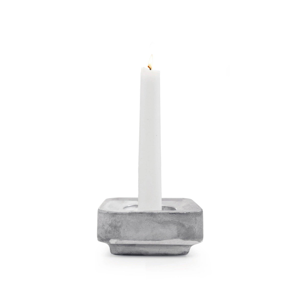 A white candle stands upright in the Stumpastaken Ettan candle holder, made from 100% recycled material and finished in white powdercoat (8.8x8.8x4 cm), against a white background.