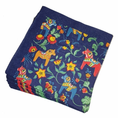 A vibrant stack of Leksand Blue Napkins showcases orange, red, and blue Swedish Dala Horses with kurbits on a rich dark blue background.