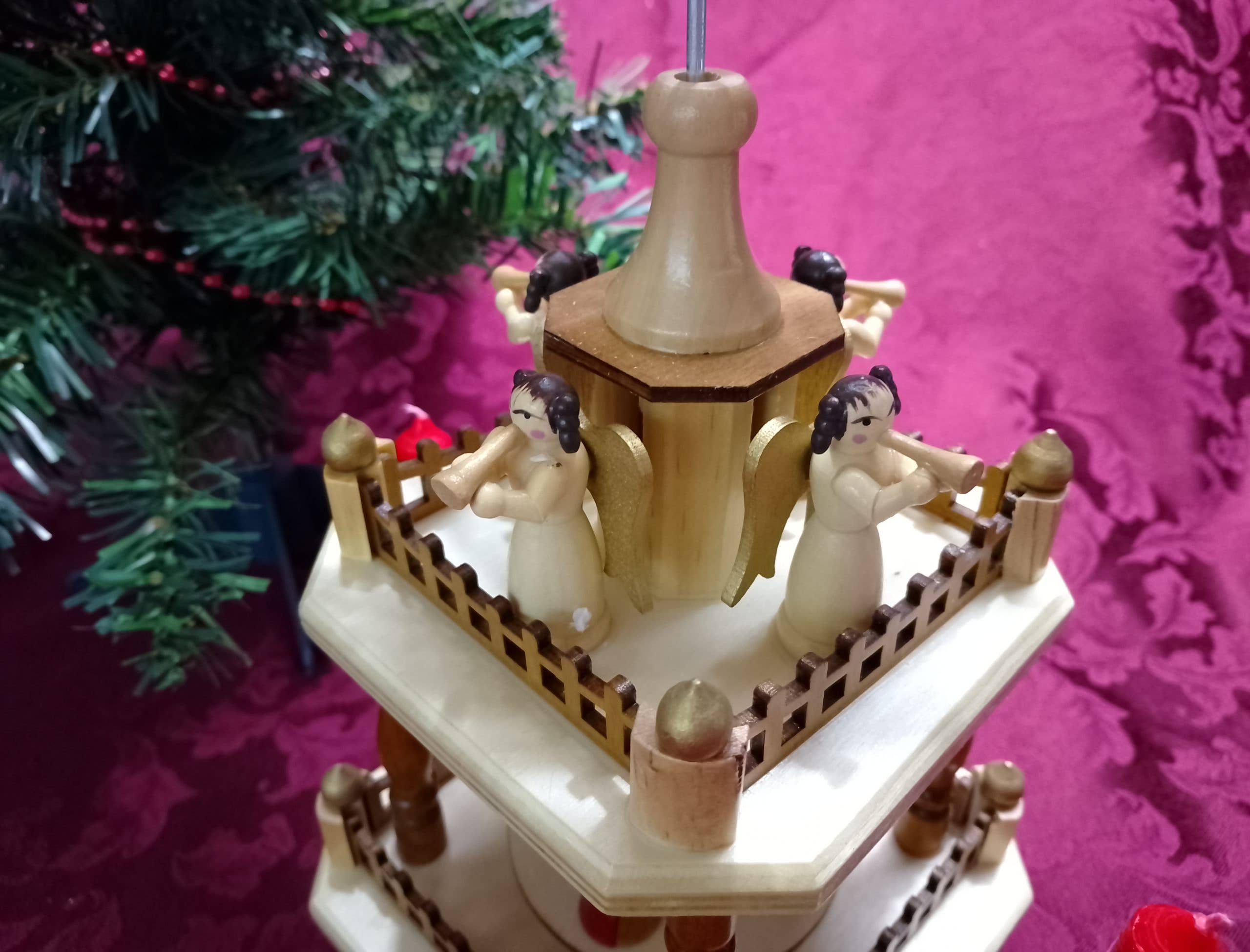 The Christmas Pyramid: Nativity Square 13" Tall features four angel figurines with instruments on the top tier, making it an enchanting wooden decoration for your nativity celebrations.