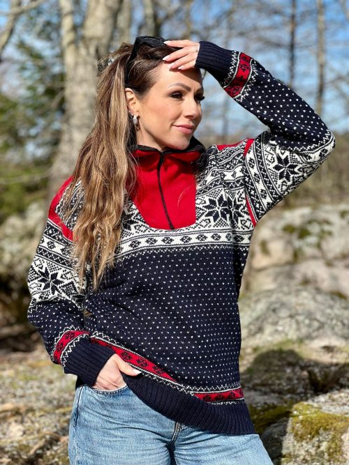 Woman wearing a navy, white, and red Norwegian wool sweater featuring a half-zip, snowflake designs, and ribbed cuffs.