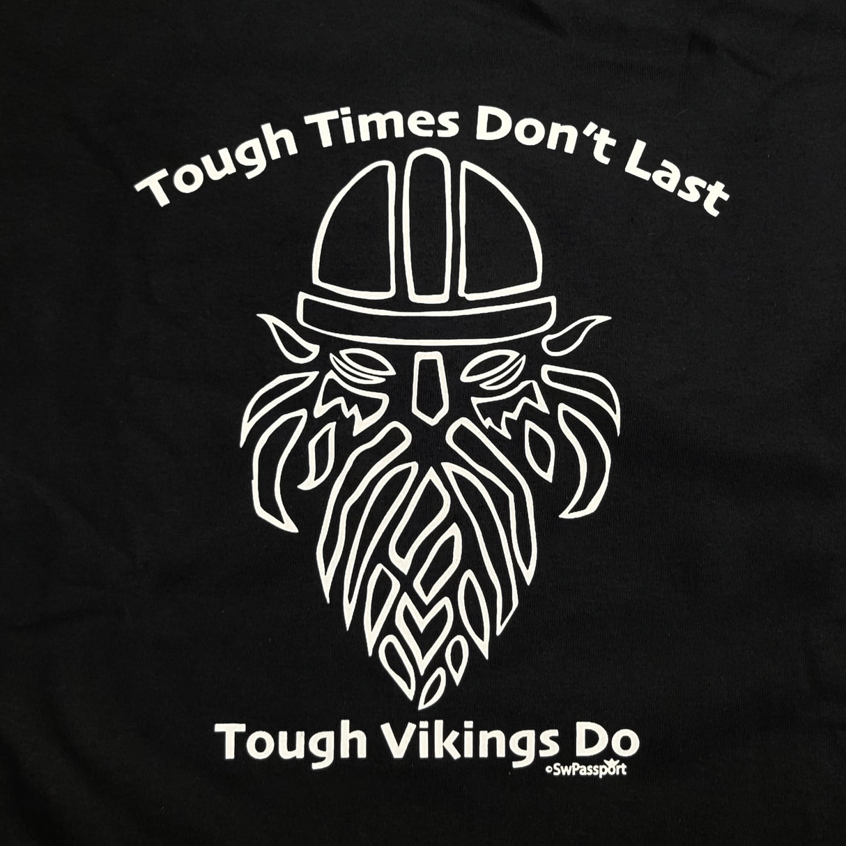 This black T-shirt, named "Tough Times Don't Last, Tough Vikings Do," features a stylized Viking helmet and beard that beautifully captures the Norse spirit with its bold design.