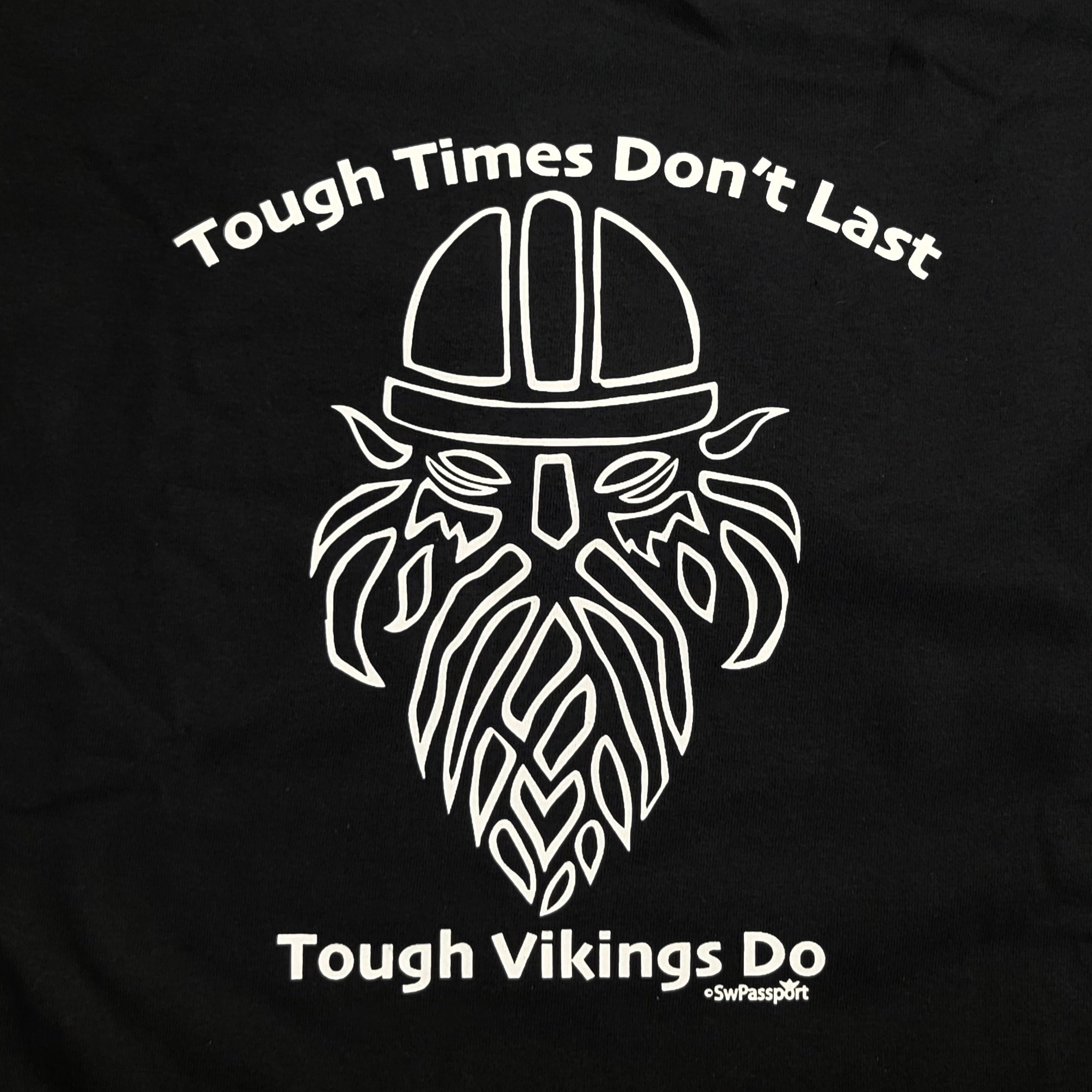 This black T-shirt, named "Tough Times Don't Last, Tough Vikings Do," features a stylized Viking helmet and beard that beautifully captures the Norse spirit with its bold design.