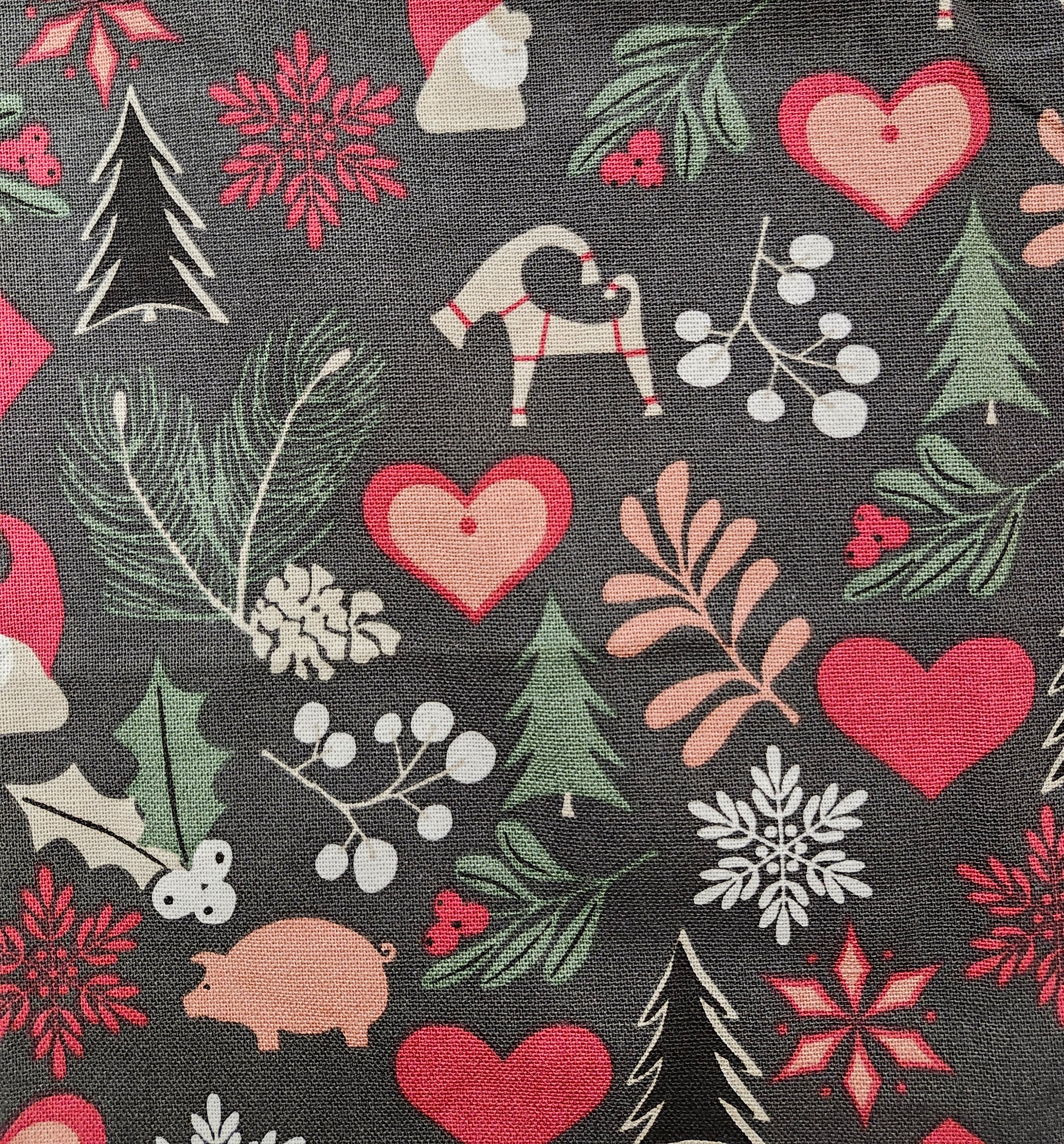 The "Julius" Apron (Dark Grey) features festive Swedish icons like tomte, straw goats, pine trees, pigs, and hearts—ideal for adding holiday cheer to your Christmas kitchen apron collection.