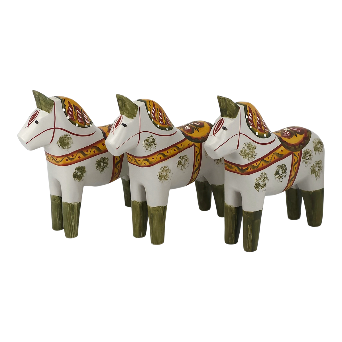 Three Dala horses with green legs, yellow and red saddles, and floral designs are arranged in a row facing left on a plain background.