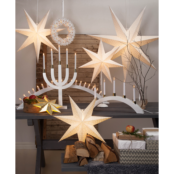 Table decorated with the Star Trading Paper Star 27.5" White, candle holders, a wreath, apples in a basket, firewood, and wrapped gifts—perfect for creating a cozy indoor atmosphere.