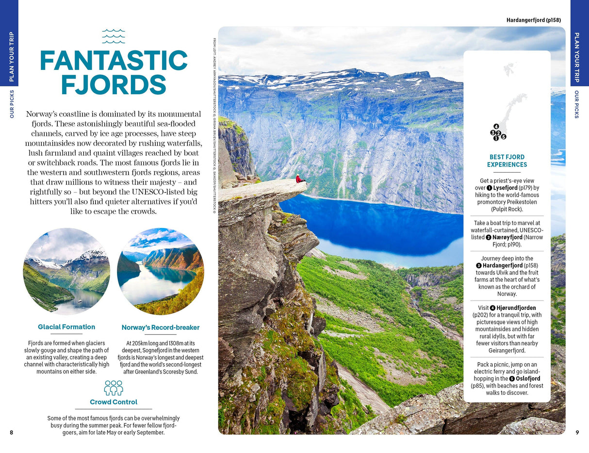 Perched on a rocky cliff above a fjord of deep blue waters, with towering green mountains and partly cloudy skies as a dramatic backdrop, people take in the stunning scenery—just like the adventures described in Hachette Book Group’s “Lonely Planet Norway Northern Lights Safari Far North Hiking & Skiing Oslo Walking Tours Travel Guide” (Paperback).
