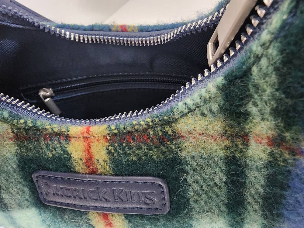 A close-up of an open Tartan Merino Wool Bag - Nova Scotia, featuring a green and yellow plaid pattern with a Patrick King label on the front.