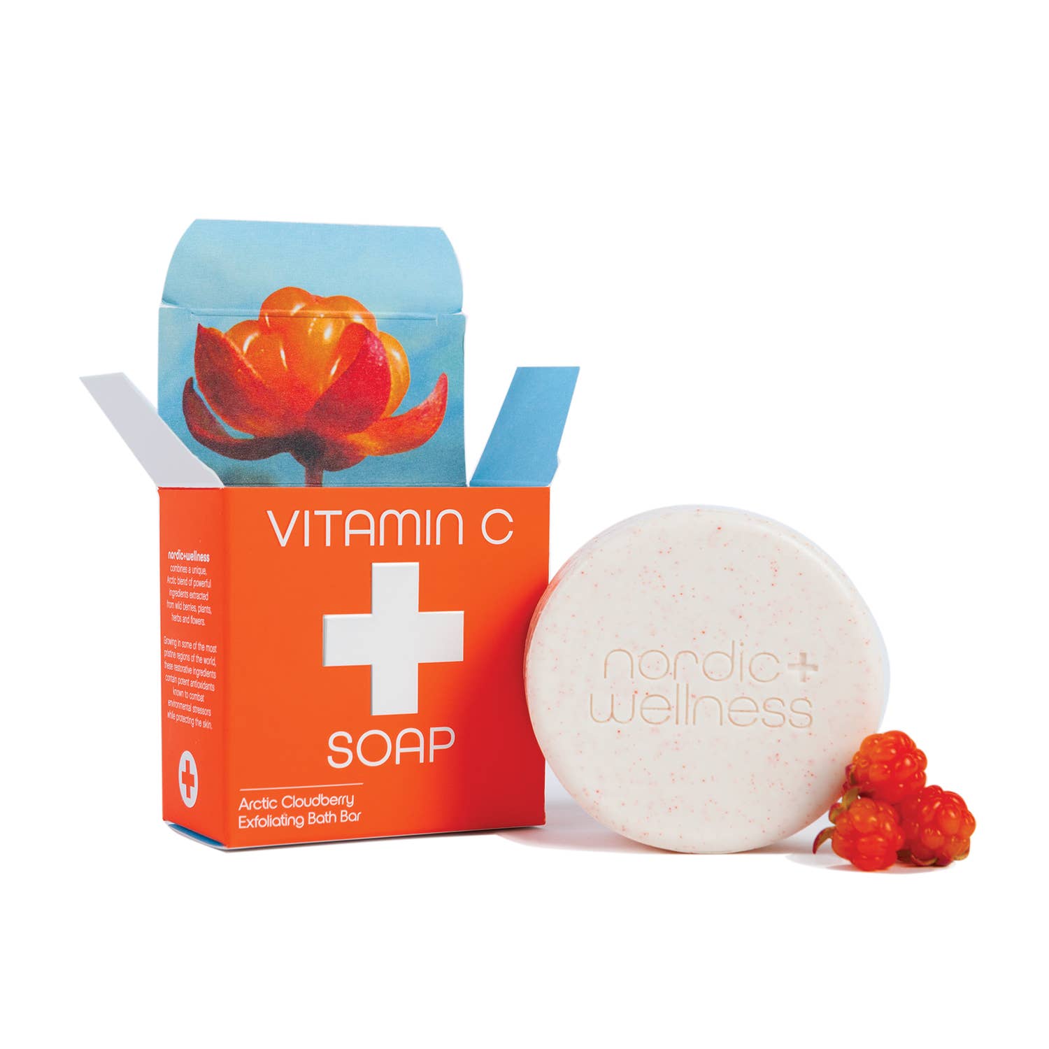 A round Nordic + Wellness Vitamin C Soap bar, its orange box, and two cloudberries on white showcase the antioxidant power and nourishing Arctic ingredients of this soap.