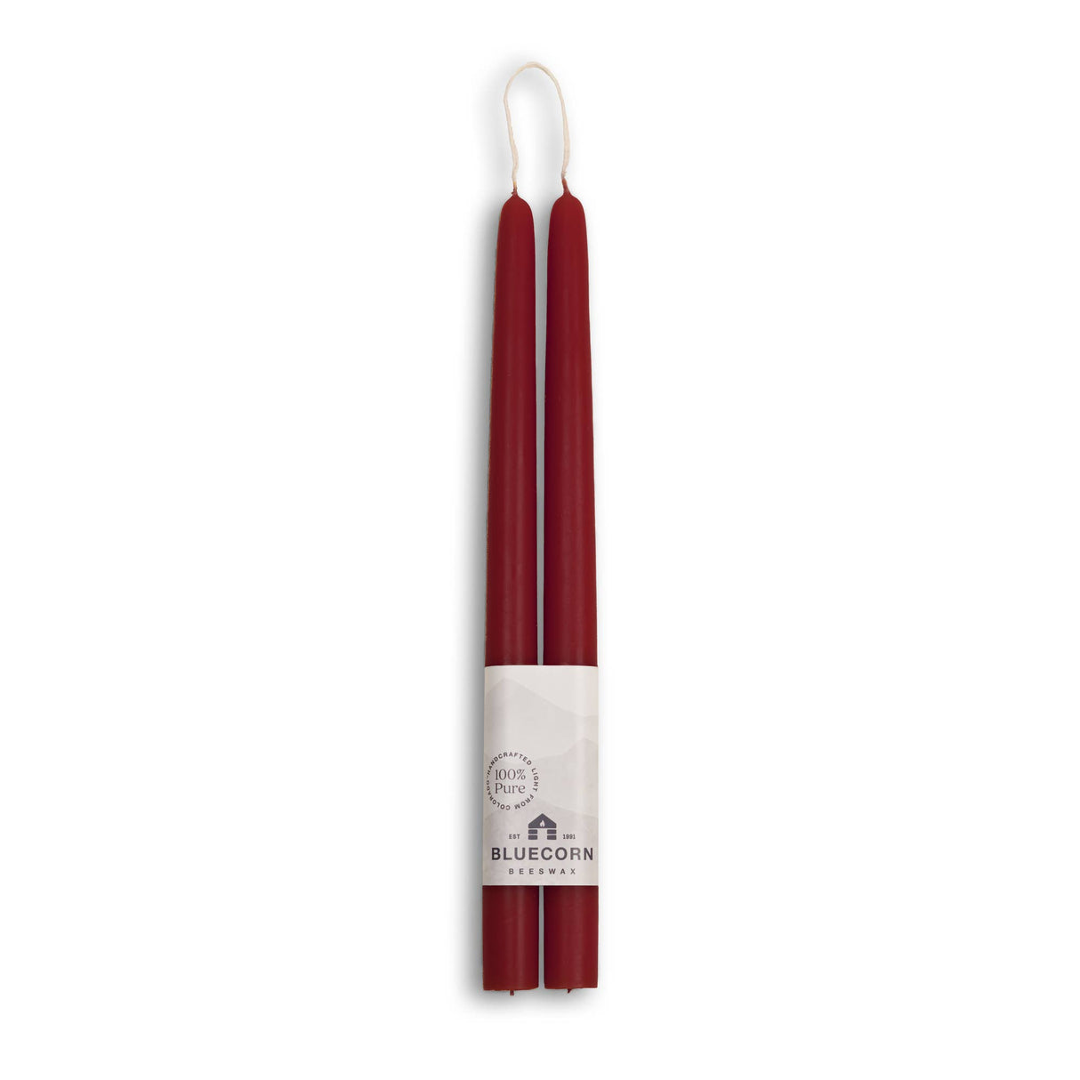 Bluecorn Beeswax offers eco-friendly, dripless taper candles; two 10-inch red beeswax candles paired in a bundle with a white brand label at the base, merging elegance and sustainability for any setting.