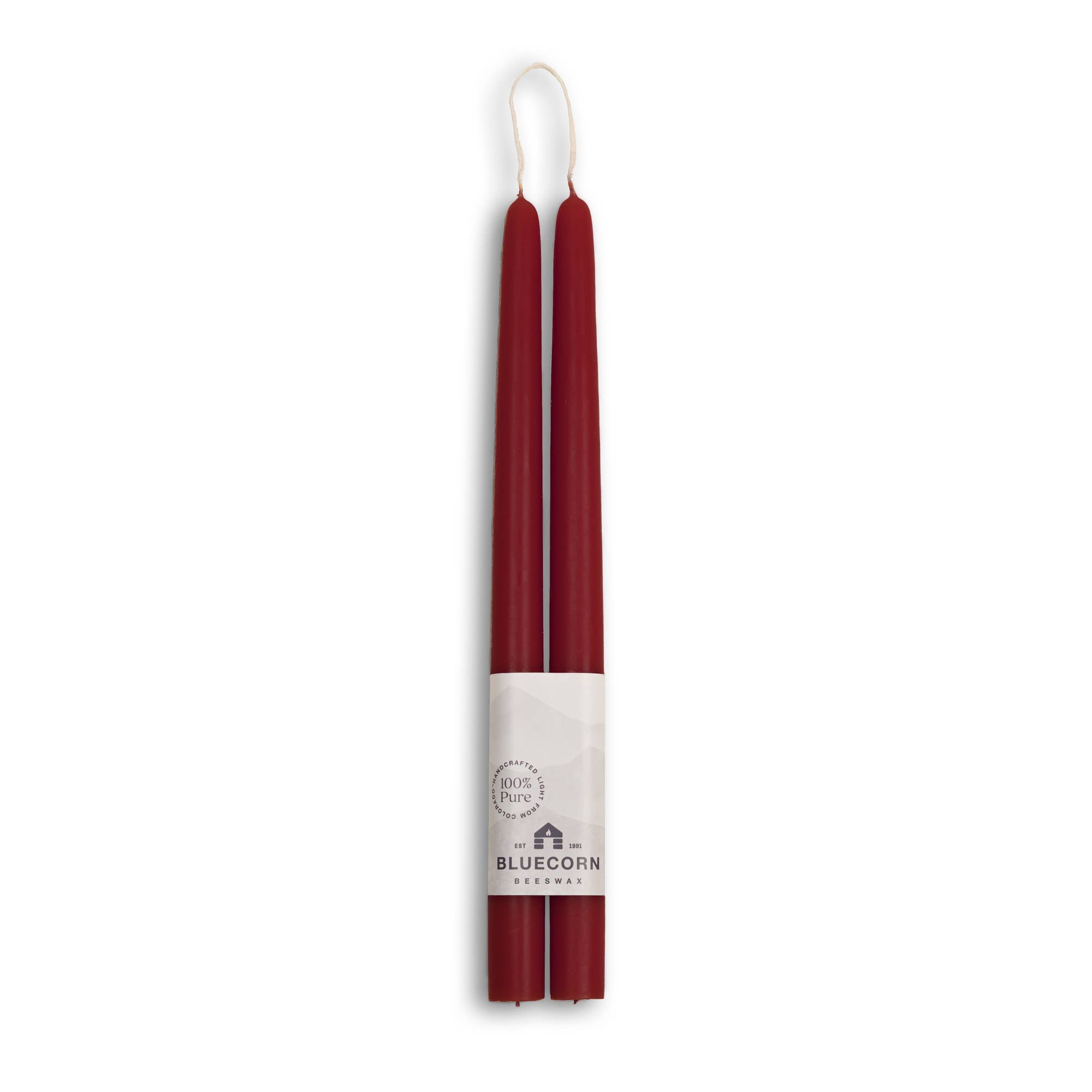 Bluecorn Beeswax offers eco-friendly, dripless taper candles; two 10-inch red beeswax candles paired in a bundle with a white brand label at the base, merging elegance and sustainability for any setting.
