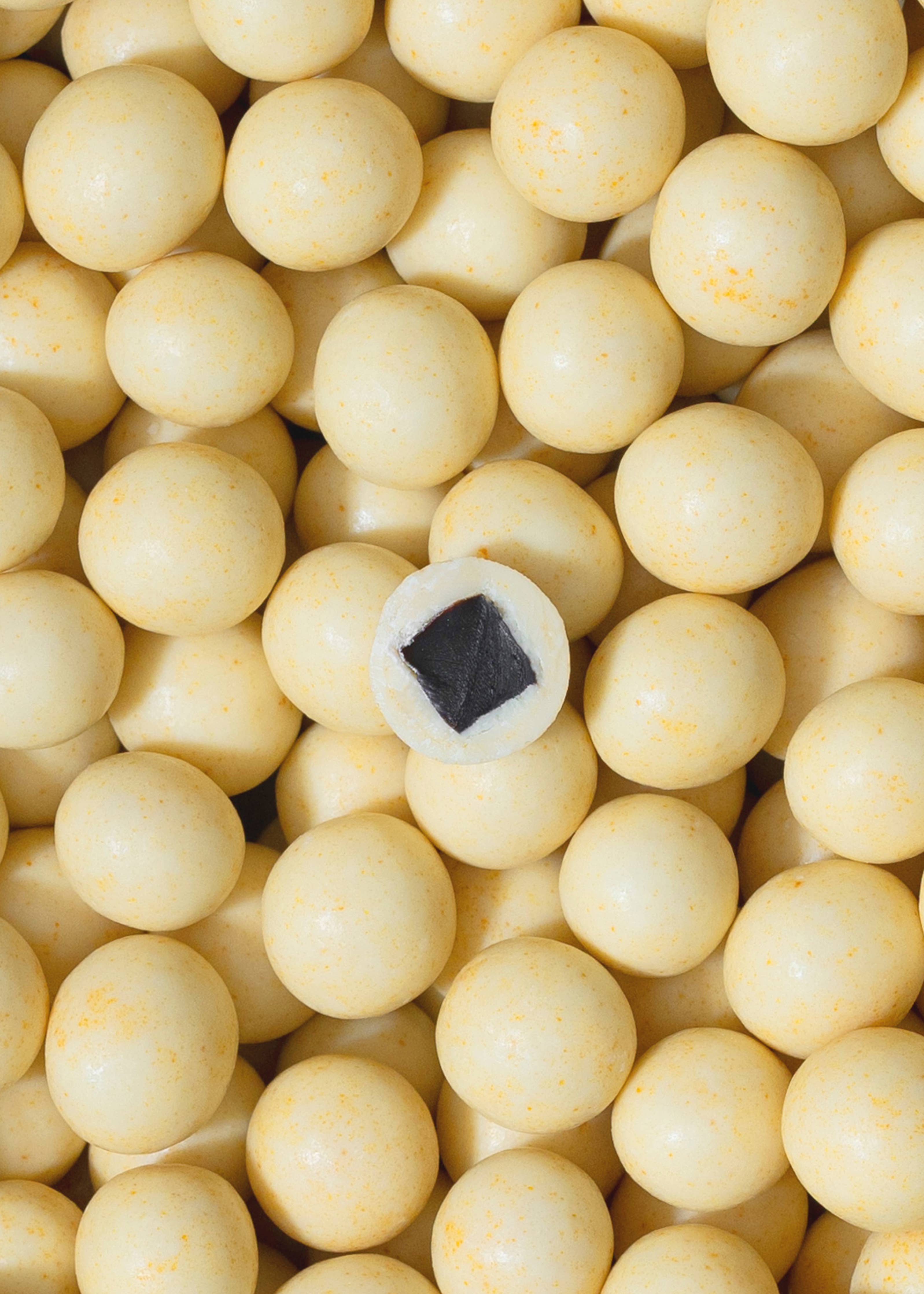 Round yellow candy pieces, one cut open to show a dark licorice center—Lakrids by Bülow Lemon (125g) combines Danish chocolate-coated licorice with zesty lemon in this limited edition treat.