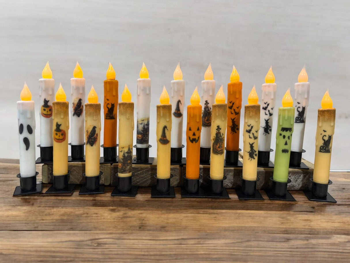 A row of Frankenstein Halloween battery-operated timer taper candles is arranged on a wooden surface.
