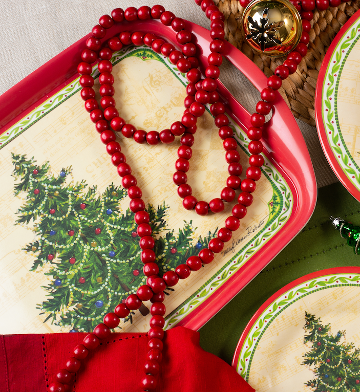 The Merry Christmas Tree Bamboo Serving Tray makes a perfect hostess gift, featuring festive dinnerware adorned with red bead garland and a gold bell ornament for an eco-friendly, holiday-inspired table setting.