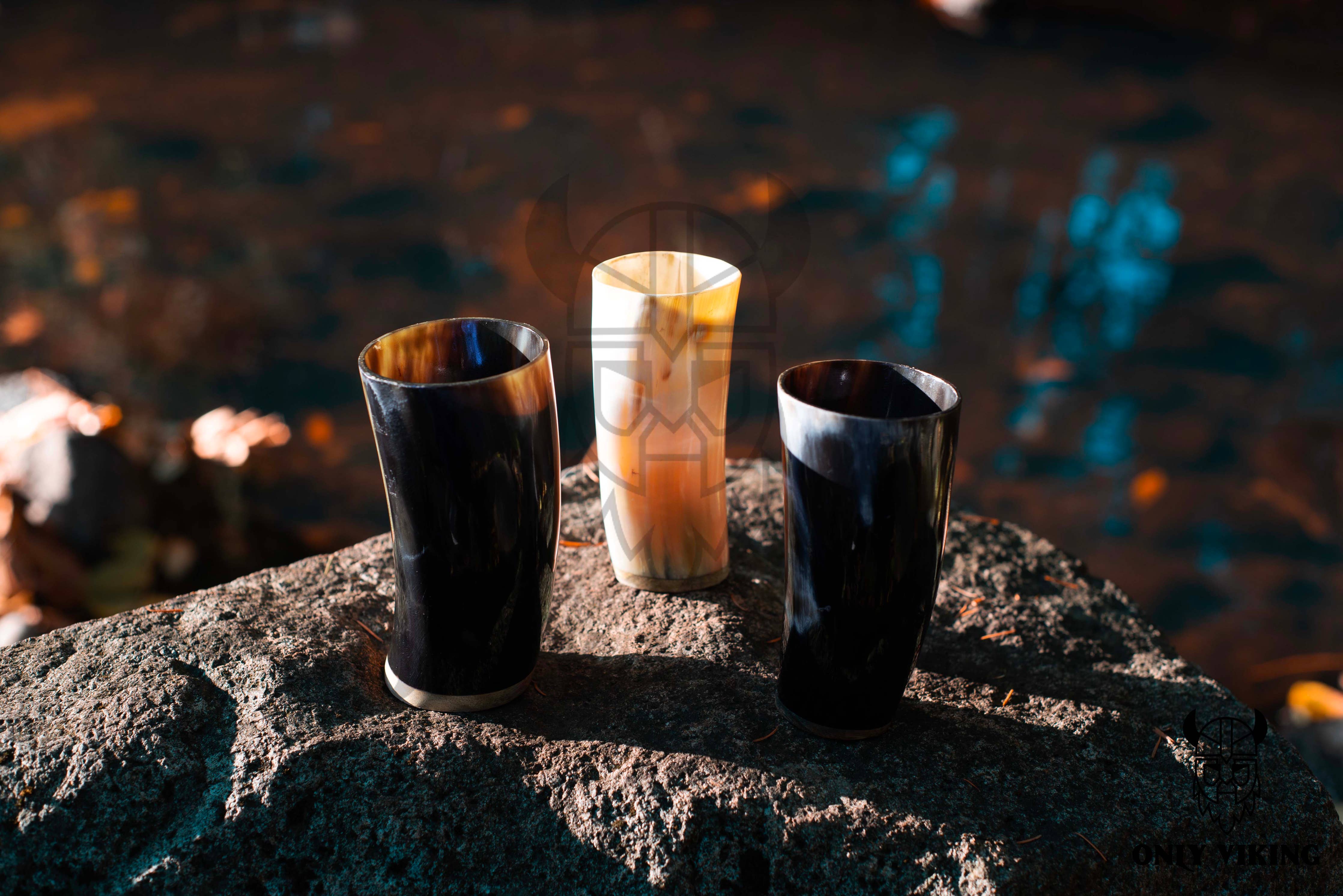 Three Drinking Horn: Beer Stein 6 Inch cups are set on a large, rough stone outdoors, with water and autumn leaves visible in the blurred background.