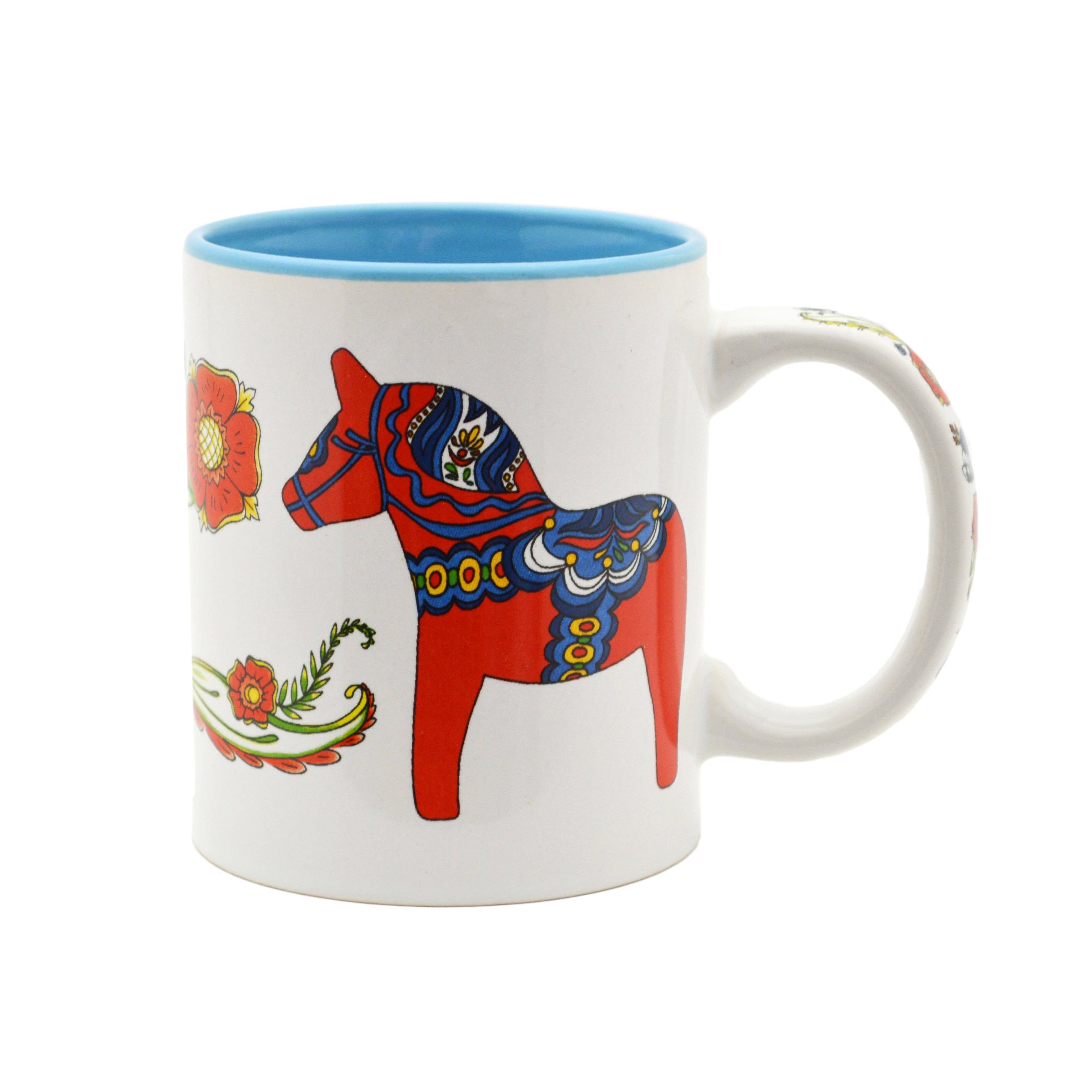 The Mug: Red Dala Horse with Blue Interior Ceramic Coffee Mug features a red Swedish Dala Horse and floral patterns, adding Scandinavian folk art style to your coffee ritual.