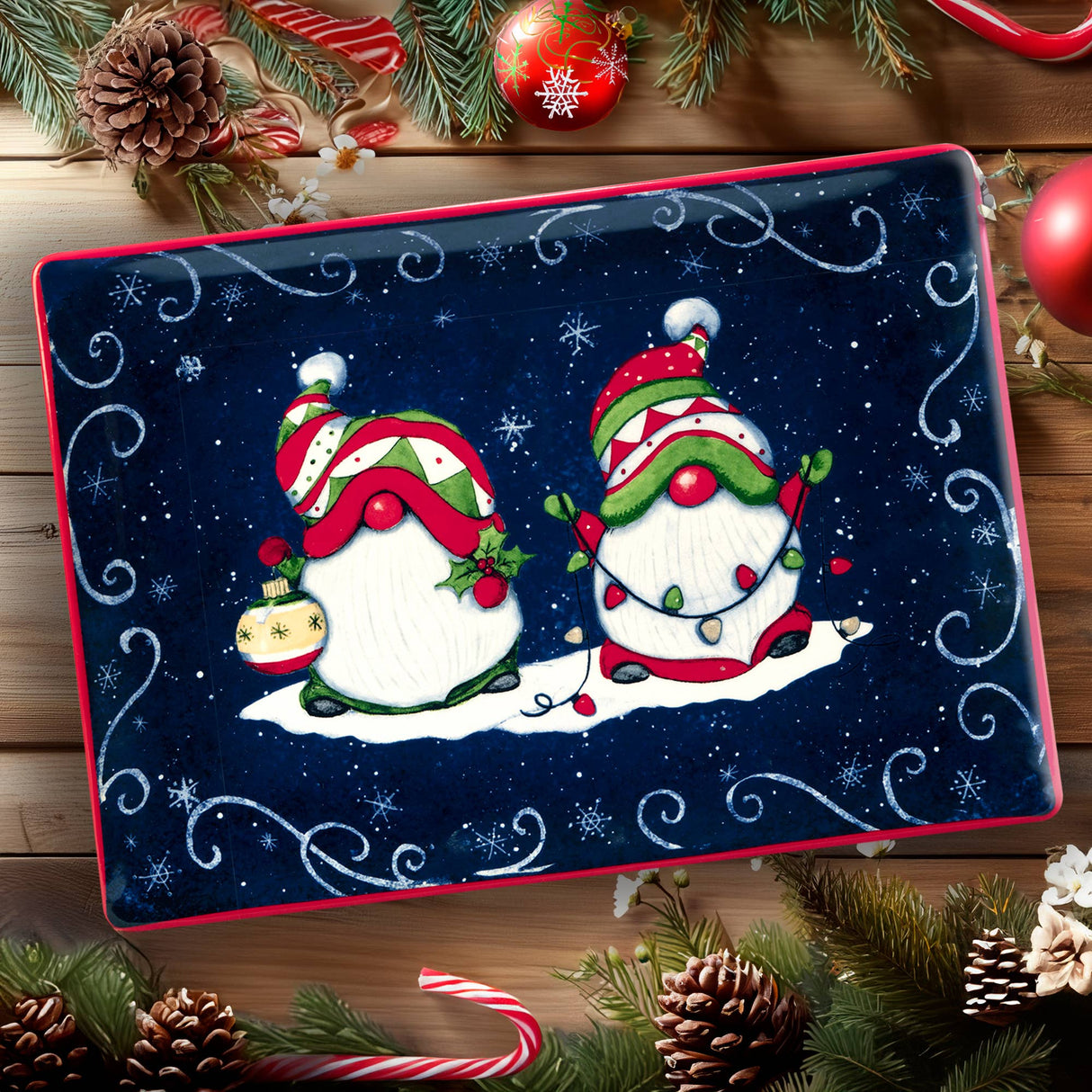 The Tray: Holiday Magic Christmas Gnomes – Rectangular Ceramic Platter (14" × 10") showcases two festive gnomes with an ornament and string lights, surrounded by snowflakes and holiday decor on a wooden surface.