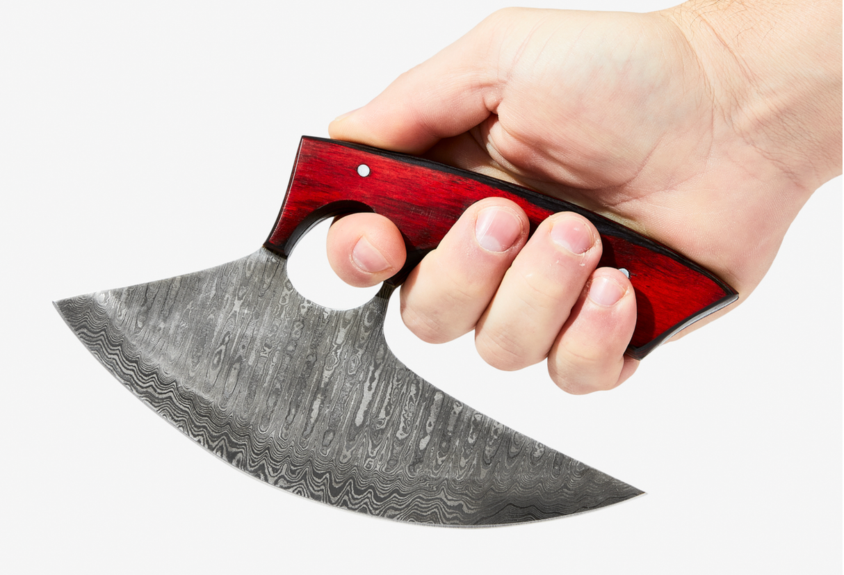 A hand holding the Knife: Alaskan Ulu Style Blade, featuring a Damascus steel blade and a red & black diamond wood handle, against a white background.