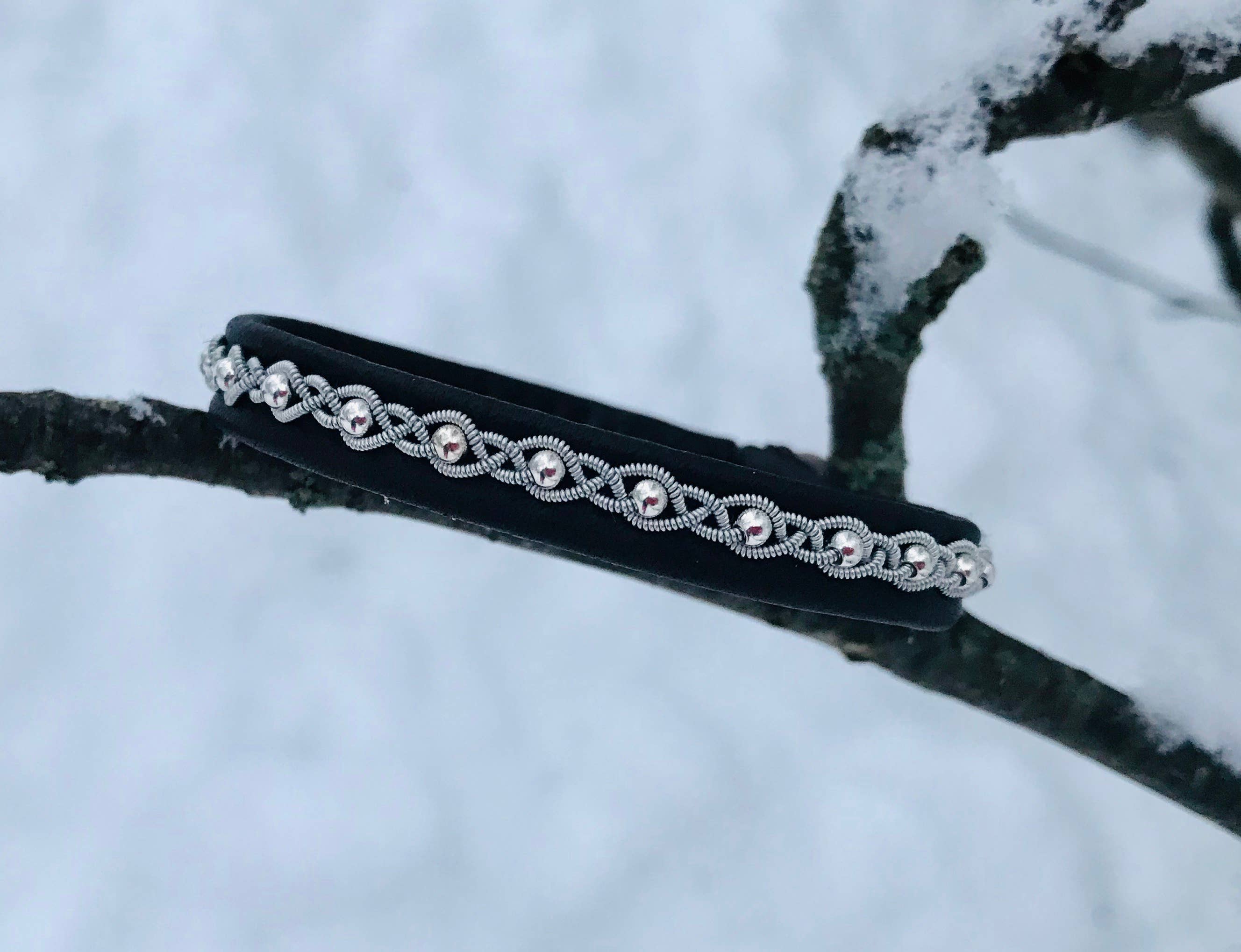 The Bracelet: Sami Lapland Bracelet With Reindeer Hide Pewter & Silver Beads #27: Black rests on a snow-covered tree branch.