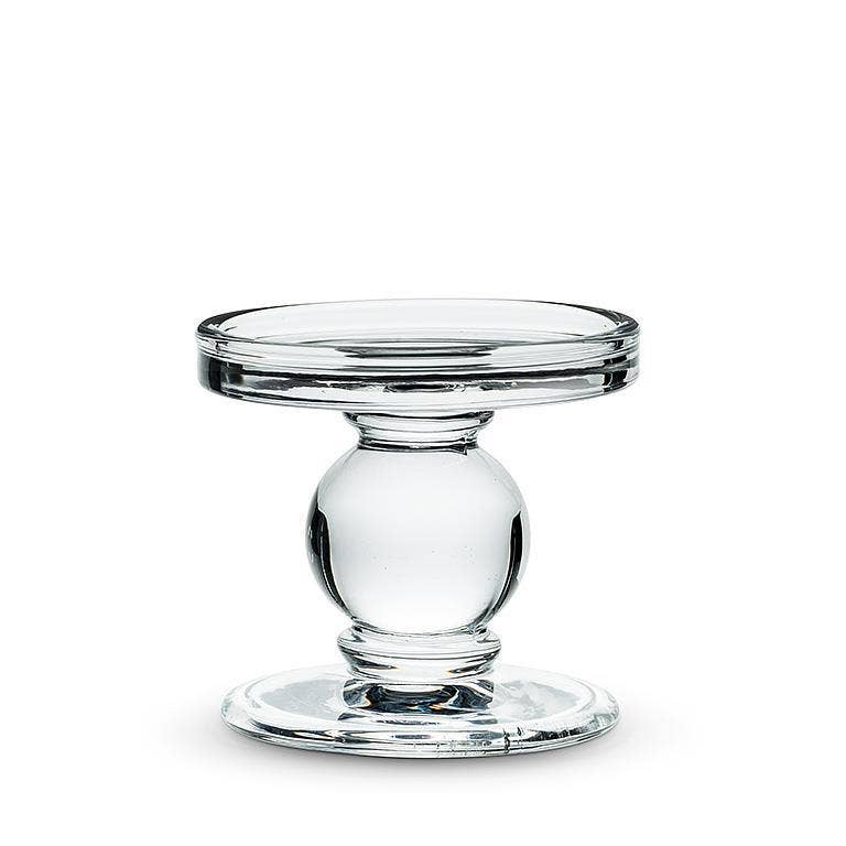 The Candle Holder: Small Reversible Candleholder-2.5"H features clear glass with a round flat top and spherical central support, doubling as a pedestal cake stand or holder for pillar candles; shown on a plain white background.