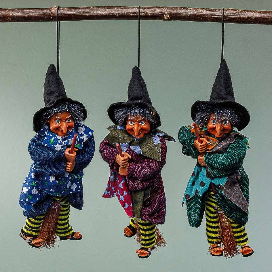 The Walburga Purple Kitchen Witch Doll is handmade in Germany, featuring a black hat, colorful clothes, striped stockings, and broomstick—a whimsical good luck charm for your kitchen.