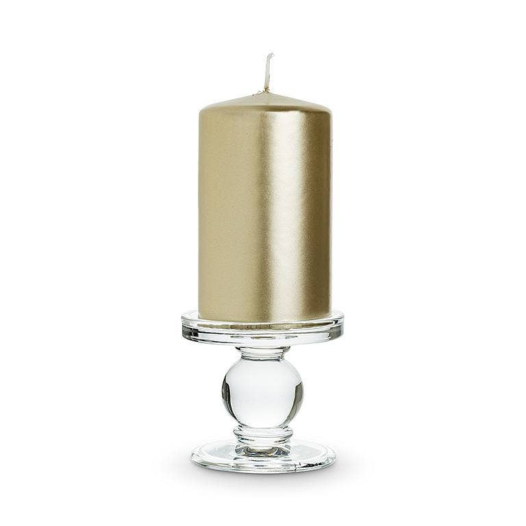 A metallic gold pillar candle sits on the Small Reversible Candleholder-2.5"H with a round base against a white background.