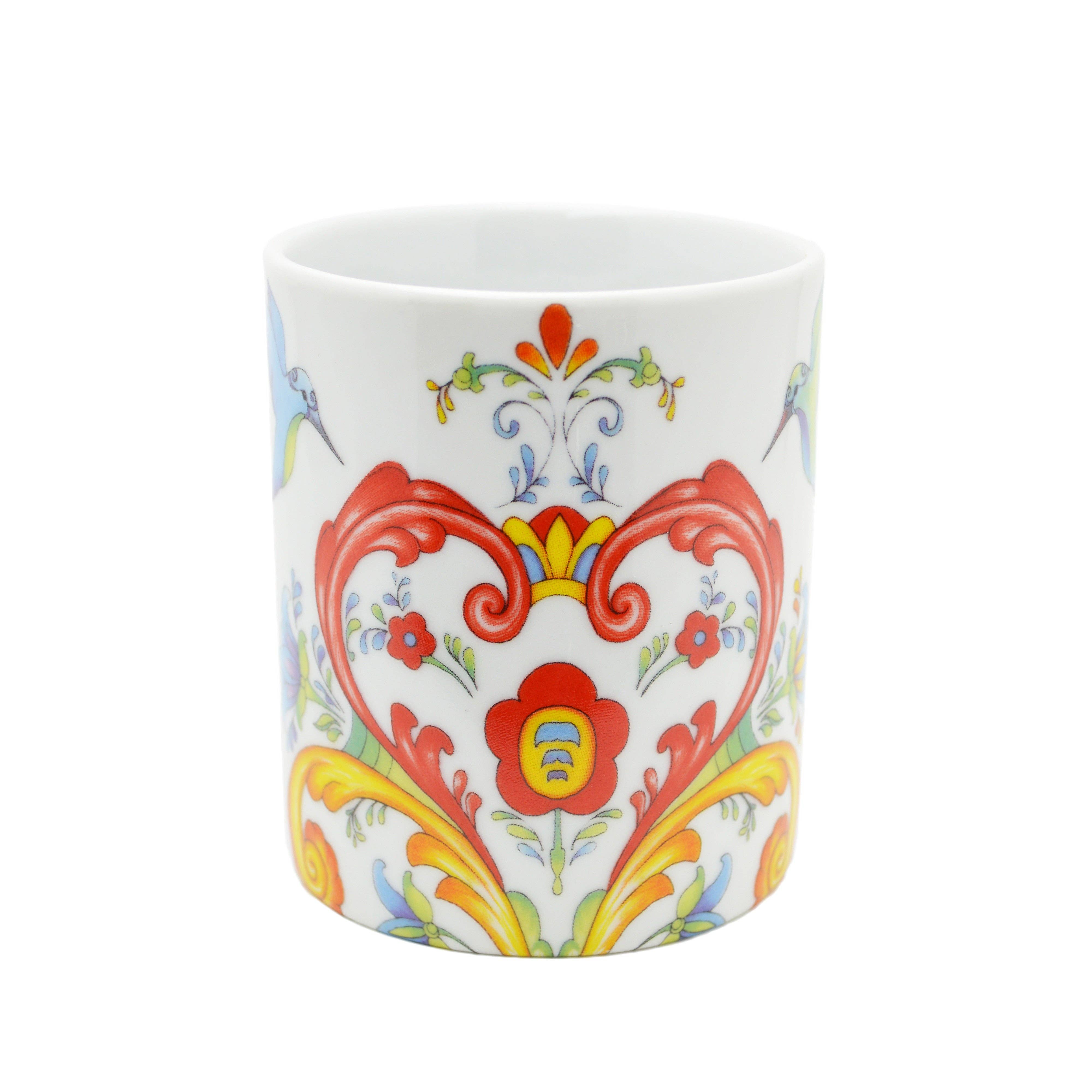 The Mug: Colorful Rosemaling Coffee Mug 12 oz is a white ceramic cup featuring vibrant red, yellow, blue, and green floral and scroll designs inspired by traditional Scandinavian rosemaling art.