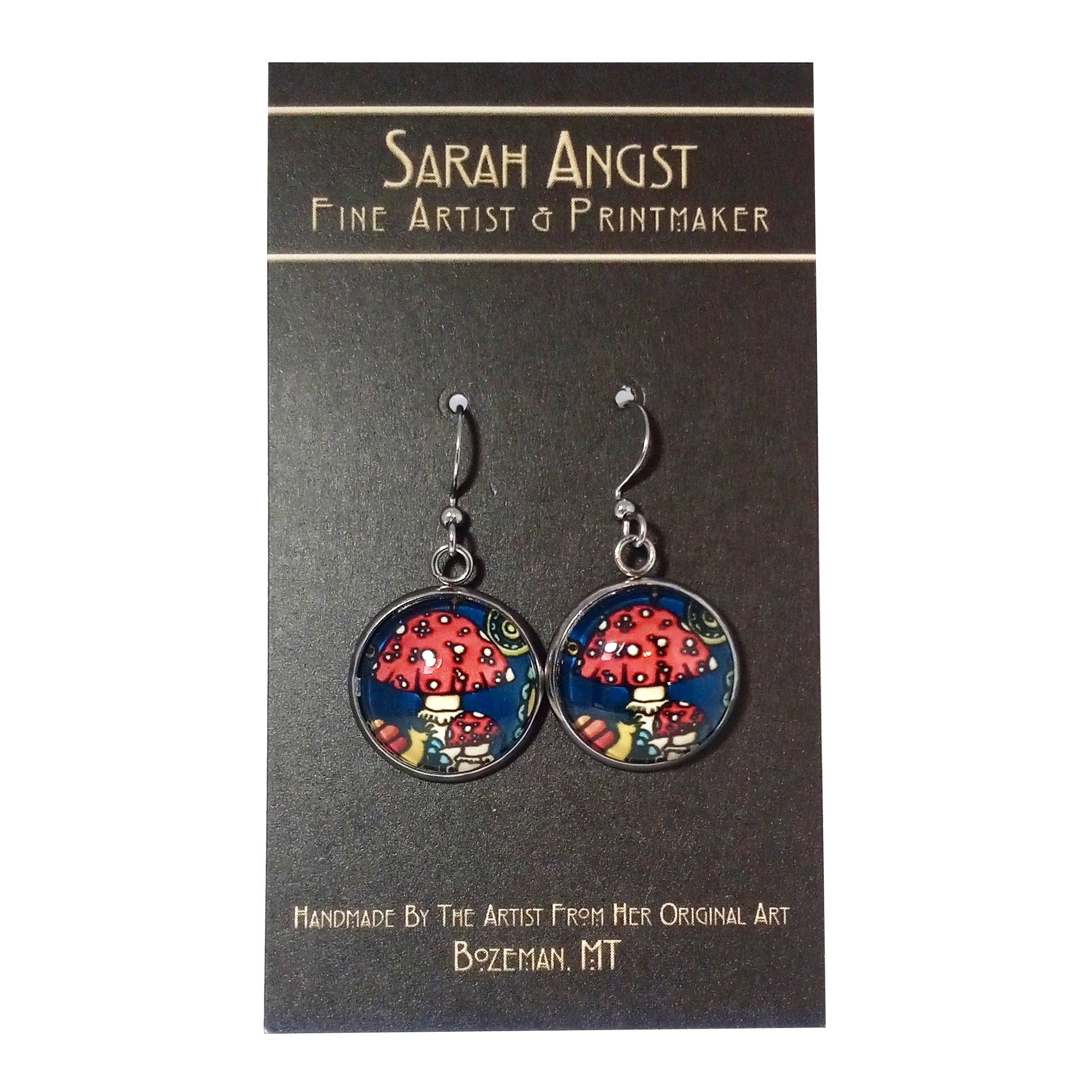 Earrings adorned with vibrant mushroom illustrations on a mini giclee print card, created by the renowned fine artist and printmaker from Bozeman, MT, Sarah Angst.
