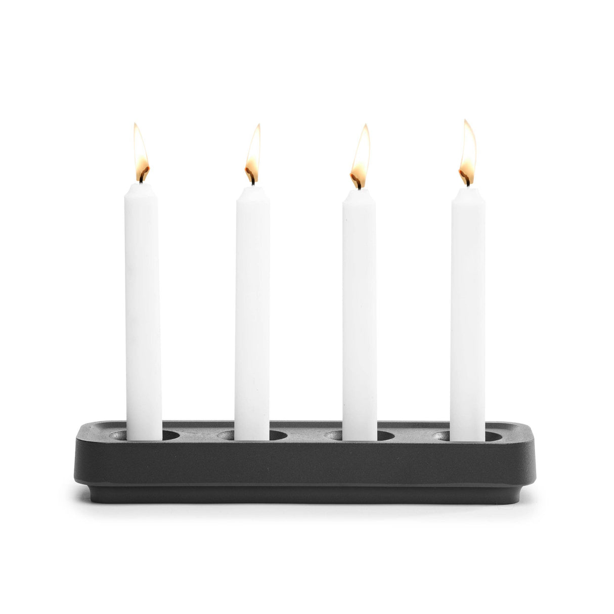Four lit white candles stand upright in the Stumpastaken Swedish Candle Holder, crafted from recycled aluminum and evenly spaced against a plain white background.