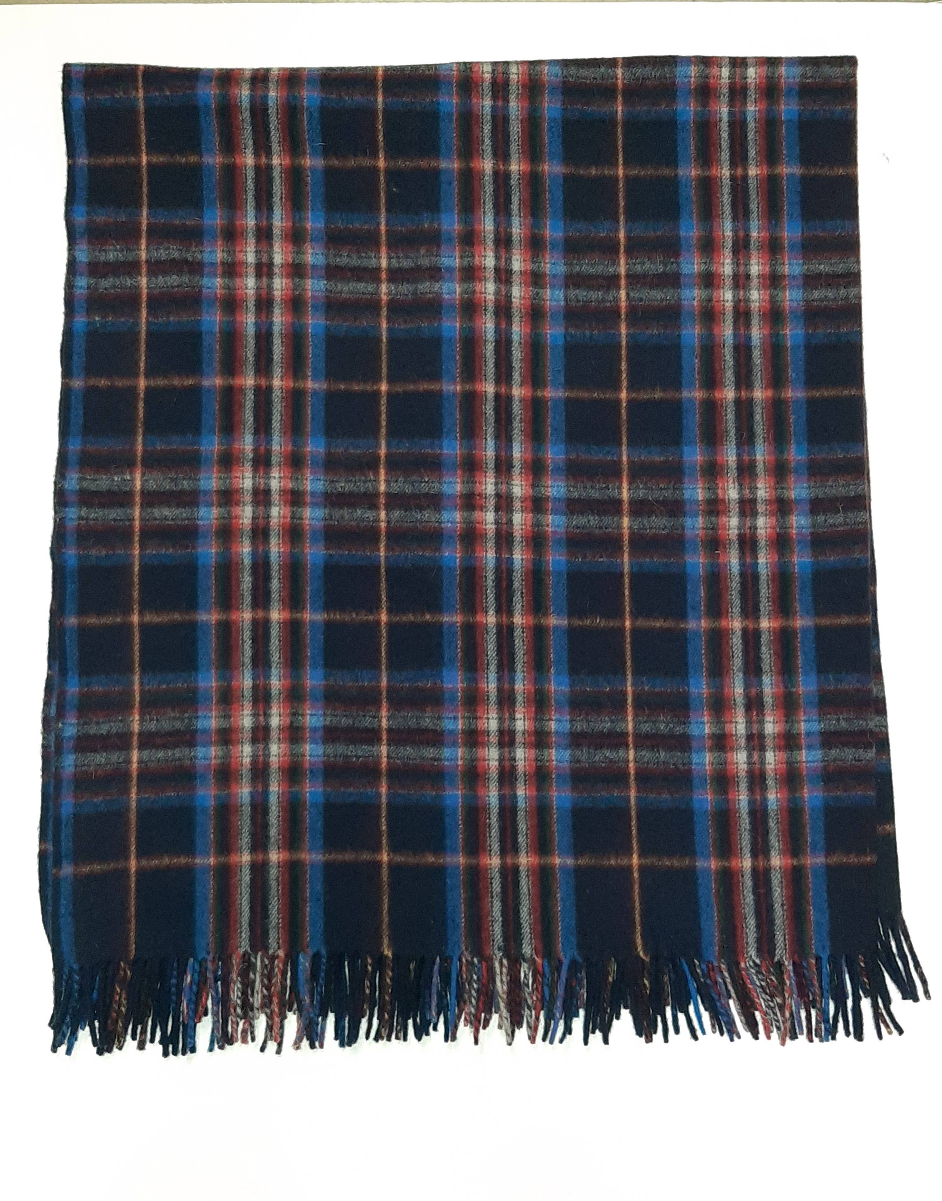 The Esprit du Quebec Deluxe Highland Blanket features a blue, brown, and red plaid pattern with fringed edges, displayed flat on a white background.