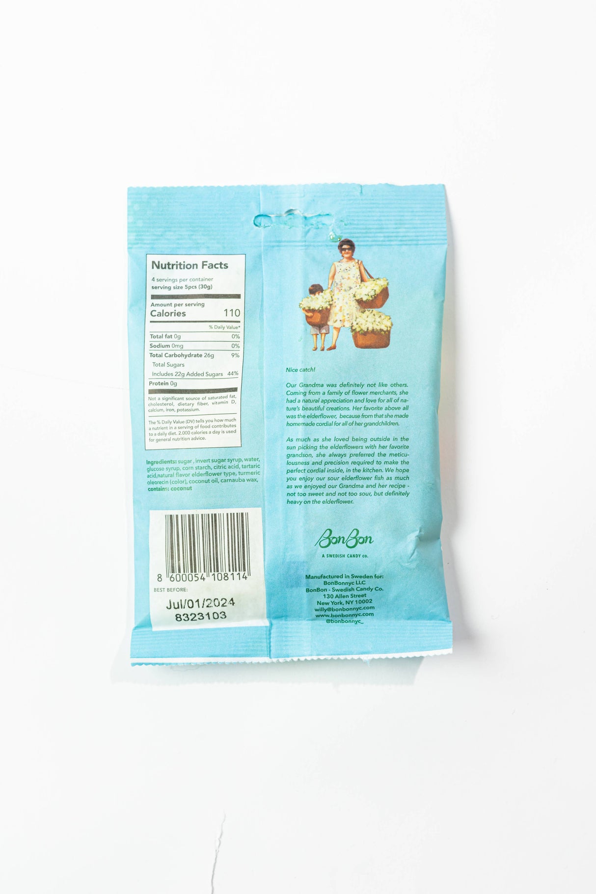 Back of a blue Candy: BonBon - Sour Elderflower Fish (150g) 5.2 oz Swedish Candy package showing nutrition facts, barcode, an illustration of a woman holding baskets, and product description for vegan and gluten-free candy.