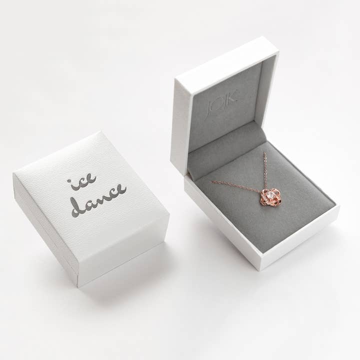 An Ice Dance Rose Gold/Sterling Silver necklace with brilliant cut cubic zirconia and an 18 chain is displayed in an open gray and white jewelry box, next to a closed box labeled Ice Dance.