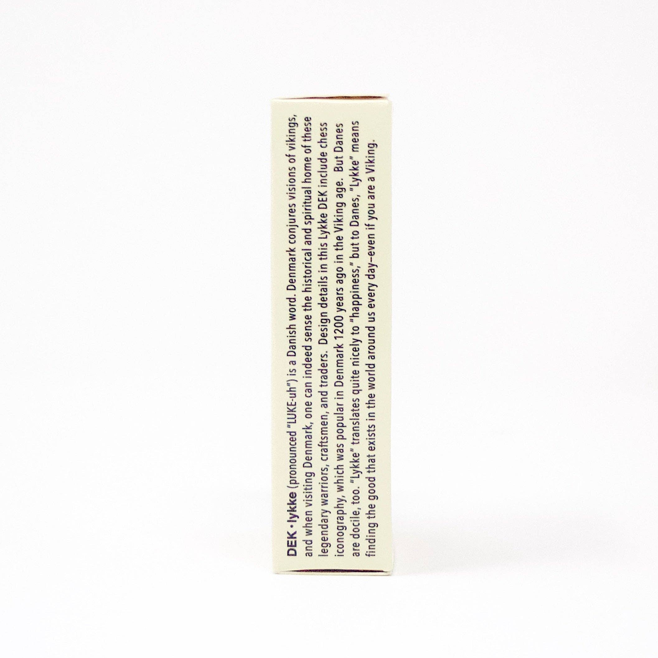 The side of the white product box for "Playing Cards: DEK Lykke (Denmark)" beautifully illustrates the Danish word "hygge," capturing a sense of coziness and comfort that brings contentment and true happiness to everyday life.