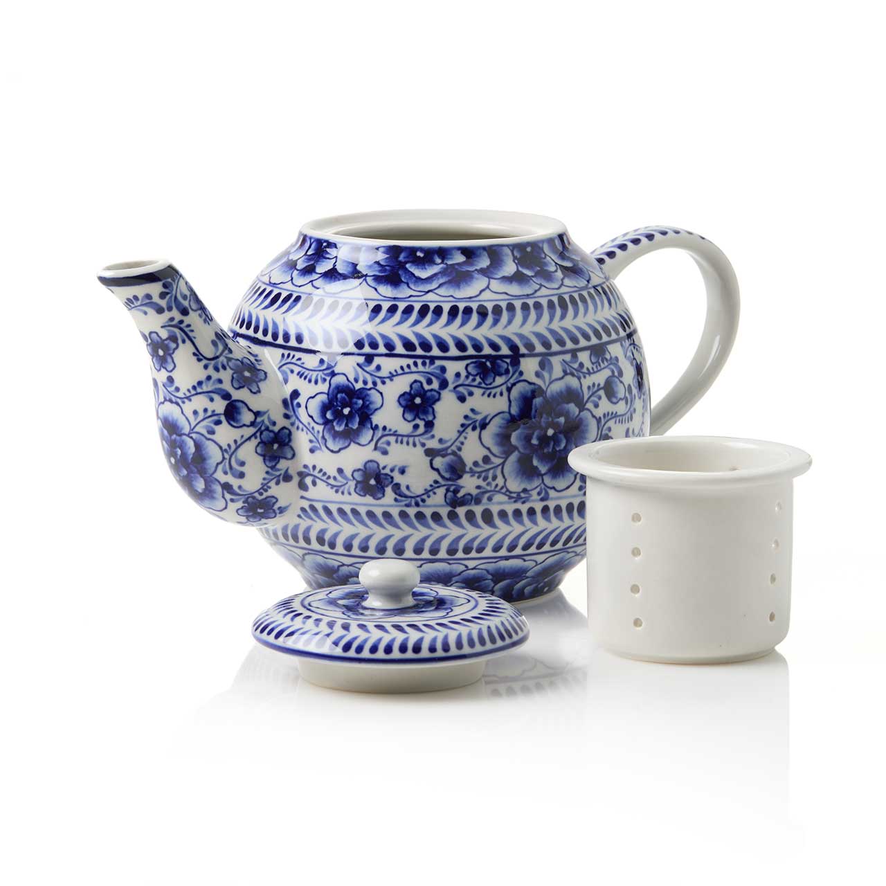 The Indigo Bloom Tea Infuser Pot, hand-painted in blue and white floral ceramic, is shown with its lid off and a matching white ceramic tea infuser beside it on a white background.